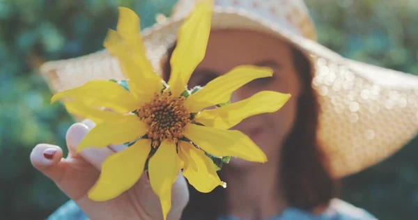 Girl in hat twists flower — Stock Photo, Image