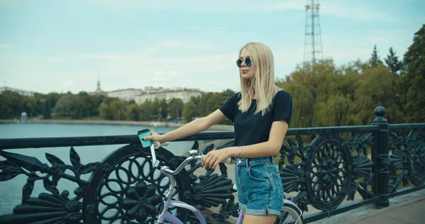 Mujer joven caminando por las calles de la ciudad con bicicleta — Foto de Stock