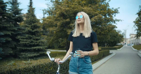 Mujer joven caminando por las calles de la ciudad con bicicleta — Foto de Stock