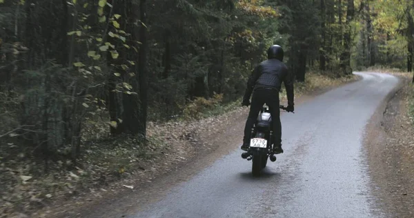 Guy rijden motorfiets op bosweg — Stockfoto