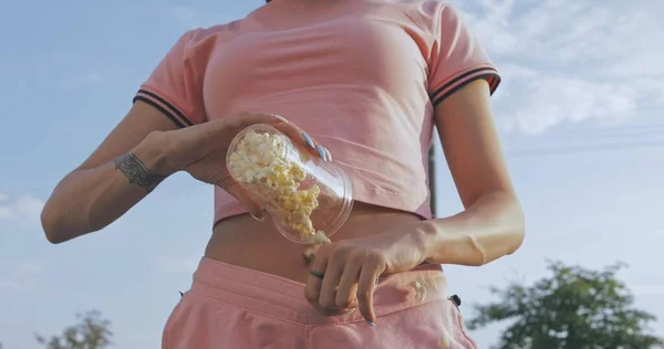 Kız pembe şortla patlamış mısır dolduruyor. — Stok fotoğraf