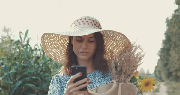 Vrouw neemt selfie op telefoon bij zonnebloem veld — Stockfoto