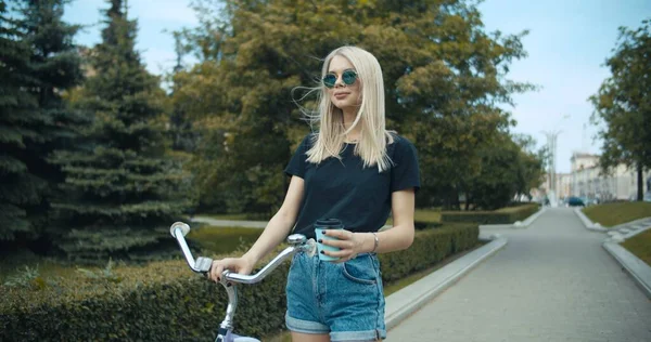 Mujer joven caminando por las calles de la ciudad con bicicleta — Foto de Stock