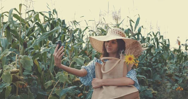 Frau macht Selfie mit Handy auf Sonnenblumenfeld — Stockfoto