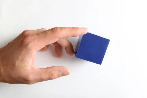 Mão tocando pequeno cubo azul — Fotografia de Stock