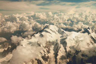 Karla kaplı Alpler ve bulutlar uçak penceresinden görünümü