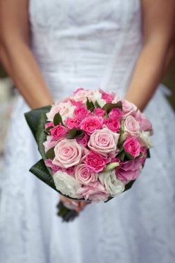 Gelin, beyaz, pembe ve mor güller güzel bir buket tutuyor