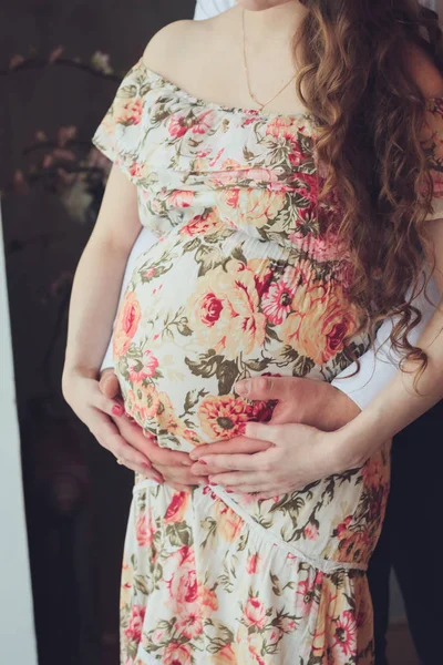 Mulher grávida em um belo vestido colorido e seu marido abraço — Fotografia de Stock