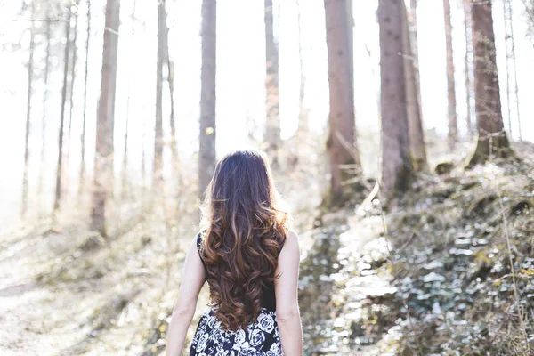 Porträt einer Frau mit schönen langen Haaren, die an einem sonnigen Tag in einem Wald spaziert — Stockfoto