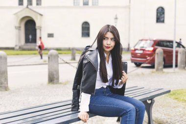 Uzun siyah saçlı genç kadın açık portresi, oturma ve bir siyah ceket giyen bir kız