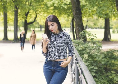 Bir cep telefonu kullanarak ve kulaklık ile müzik dinleme genç gülümseyen kadın