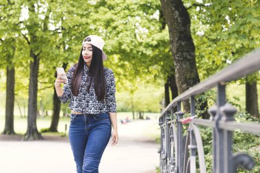 Bir cep telefonu kullanarak ve kulaklık ile müzik dinleme genç gülümseyen kadın