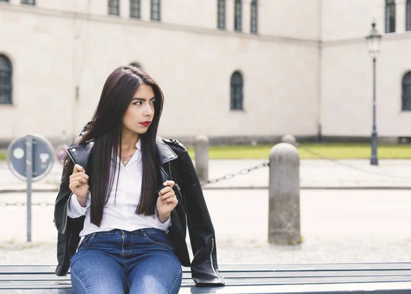 Uzun siyah saçlı genç kadın açık portresi, oturma ve bir siyah ceket giyen bir kız