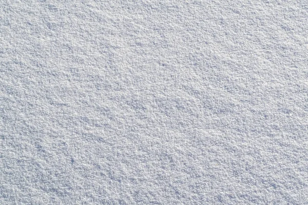 The texture of pure white snow. Close up of fresh clean snow with blue shadows.