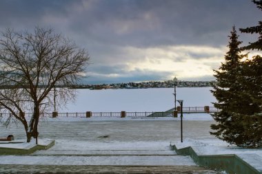 Kış mevsimi, gün batımında şehrin göletindeki ilk kar manzarası. Parkın ilk karı..