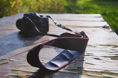 Eski ahşap bir masada, güneş ışığına karşı kamera ve bulanık bir arka plan..