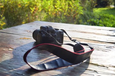 Eski ahşap bir masada, güneş ışığına karşı kamera ve bulanık bir arka plan..
