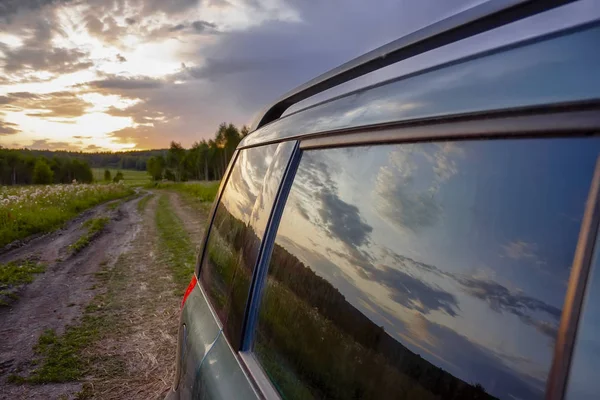 Вечерний летний пейзаж. Цветной закат отражается в автомобильном стекле . — стоковое фото