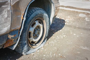 Terk edilmiş eski, paslı, patlak bir araba. Yakın plan. Yakın çekim hasarlı lastik..