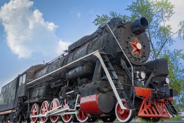 Mavi gökyüzünün arka planında Sovyet sembolleri olan klasik buhar treni..