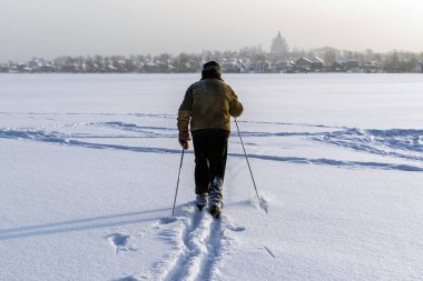 Kayakçı donmuş bir göleti geçer. Güneşli bir kış sabahı pistte bir kayakçı.