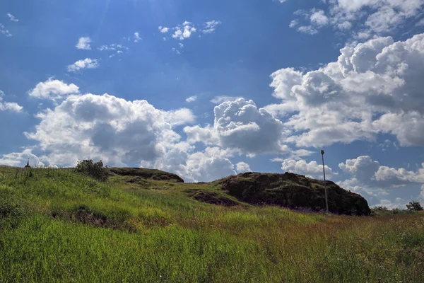 Paysage estival. Prairie avec des herbes des champs sur une pente sur un fond de ciel bleu et de nuages blancs . — Photo