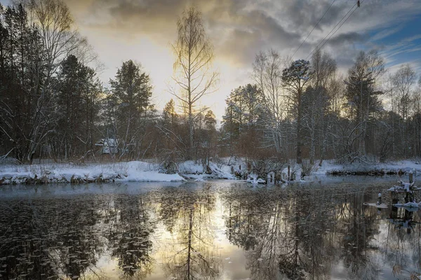 Winterlandschap bij zonsondergang door een besneeuwd bosmeer. Winterbos. — Stockfoto