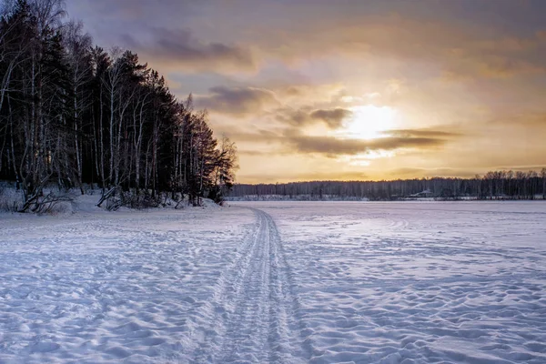 Winterlandschaft bei Sonnenuntergang an einem verschneiten Waldsee. Winterwald. — Stockfoto