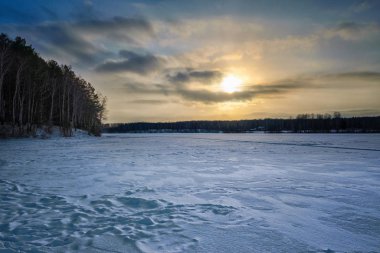 Gün batımında karlı bir orman gölü kıyısında kış manzarası. Kış Ormanı.