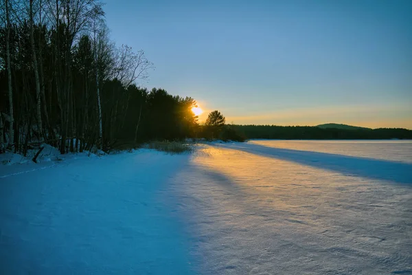 Paisagem de inverno ao pôr do sol por um lago de floresta nevada. Floresta de Inverno . — Fotografia de Stock