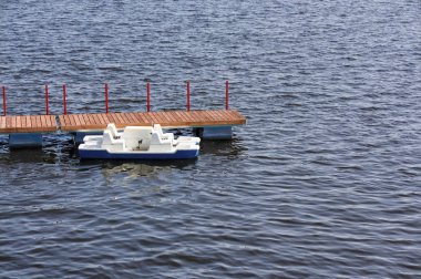 Turist katamaranı yazın şehrin göletindeki rıhtımda yürüyor..