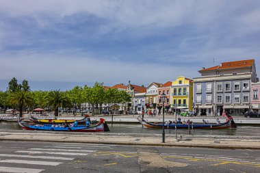 Aveiro, Portekiz - 20 Nisan 2017: Güneşli bir günde kanal üzerinde geleneksel Moliceiro teknelerinin (gondollar) bulunduğu ana şehir kanalı ve Vouga Nehri manzarası.