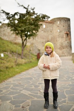 Şapkalı ve ceketli genç kız parkta yürüyor.