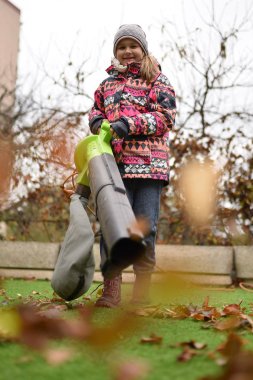 Sonbaharda yaprak üfleyicisi olan genç kız