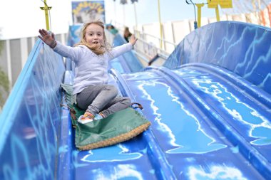 Mutlu kız çocuk kaydırağından aşağı iniyor.