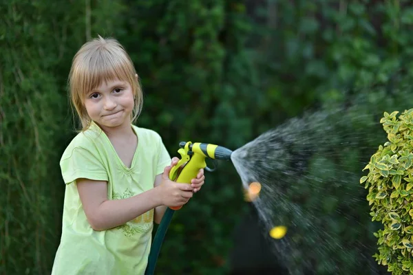 Roztomilá holčička zalévání květiny, zalévání — Stock fotografie