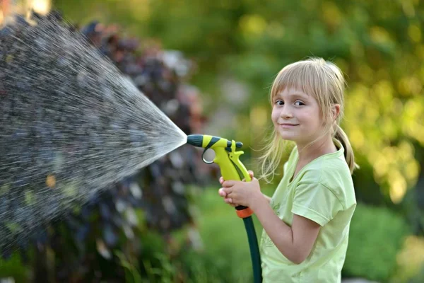 Cute little girl watering flowers watering — Stock Photo, Image