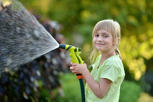 Мила маленька дівчинка поливає квіти — стокове фото