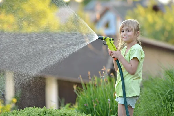 Söt liten flicka vattna blommor vattning — Stockfoto