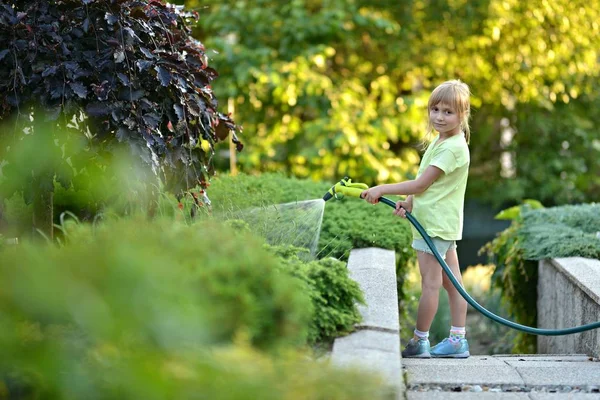 Söt liten flicka vattna blommor vattning — Stockfoto