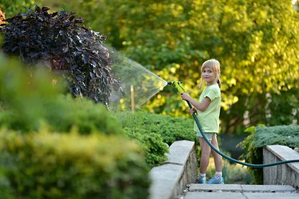 Söt liten flicka vattna blommor vattning — Stockfoto