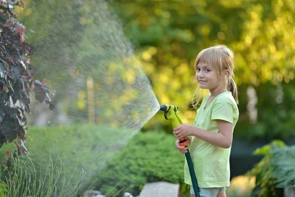 Söt liten flicka vattna blommor vattning — Stockfoto