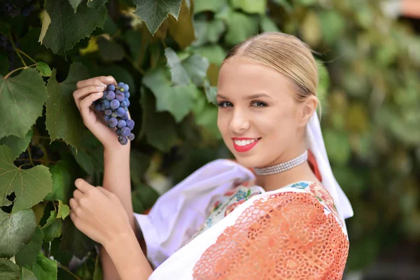 Donna sorridente mantiene l'uva in mano all'aperto — Foto Stock