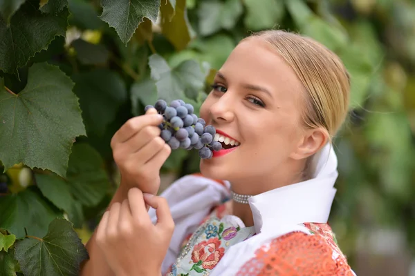 Smiling woman keeps grapes in hands outdoor — Stock Photo, Image