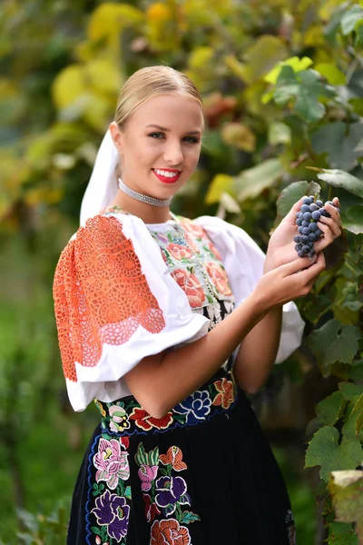 Mujer sonriente mantiene las uvas en las manos al aire libre — Foto de Stock