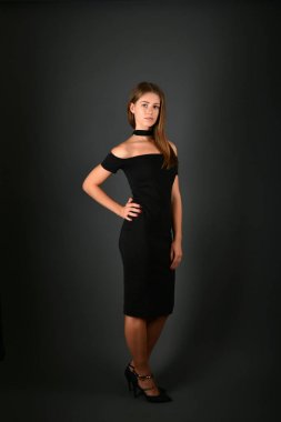 gri arka plan üzerinde poz siyah elbiseli genç esmer Bayan