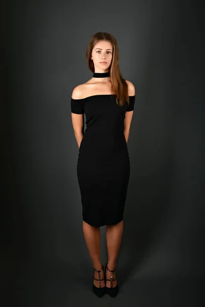 Young brunette lady in black dress posing on grey background — Stock Photo, Image