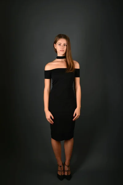 Молодая брюнетка в черном платье позирует на сером фоне — стоковое фото