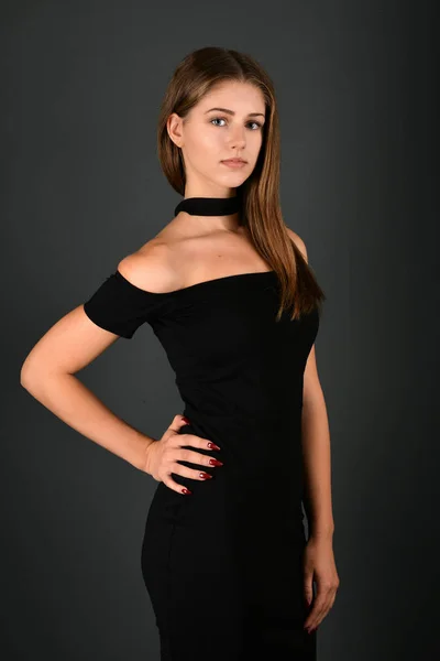 Joven morena en vestido negro posando sobre fondo gris —  Fotos de Stock