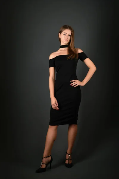 Young brunette lady in black dress posing on grey background — Stock Photo, Image